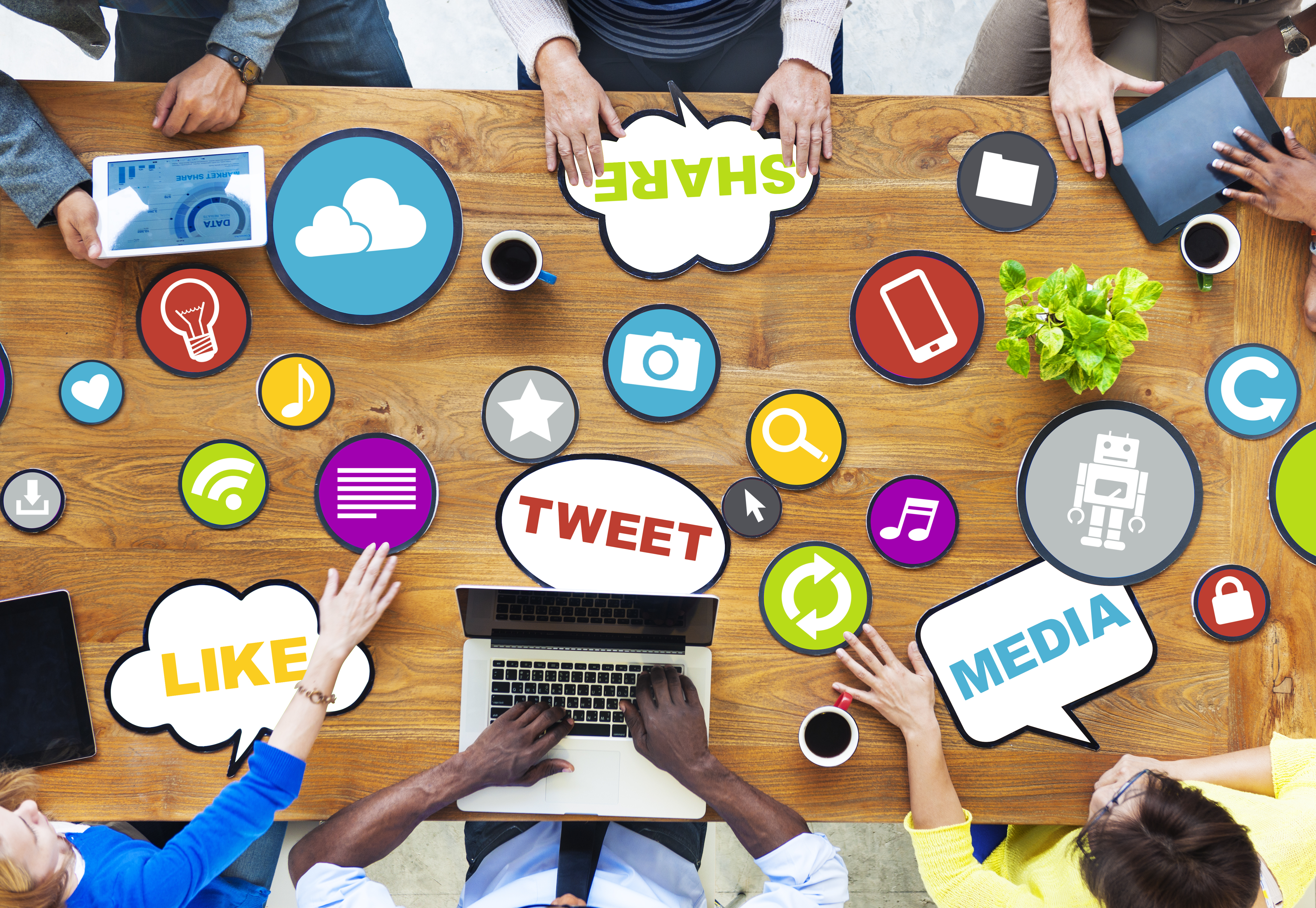 an aerial view of a team meeting at a large table with differnt pictures and word clouds related to social media